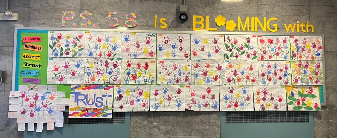 Large collaborative student art showing many colorful flowers made my hand prints, titled PS 58 is Blooming with friendship, kindness Respect Trust and Diversity